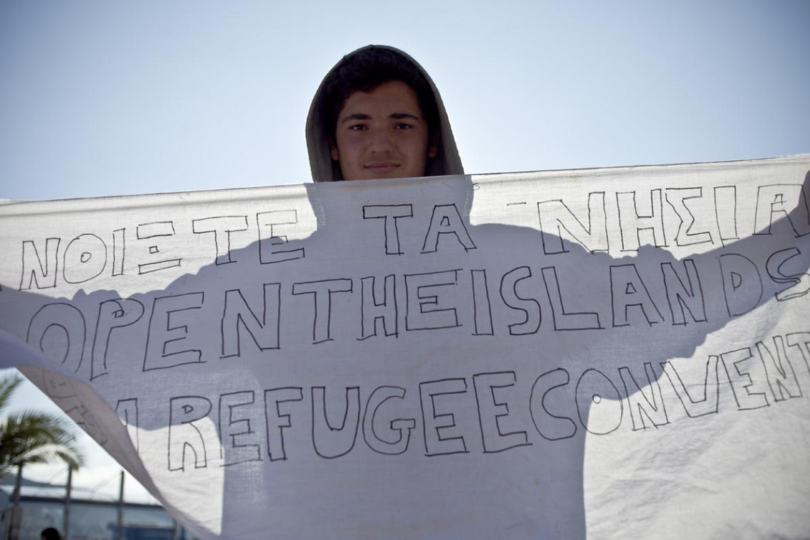 Een vluchtelingen houdt een spandoek omhoog bij een betoging in Mythilini